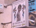This tattoo shop sign with a kid showing off his tribal tattoo might make you say WTF!