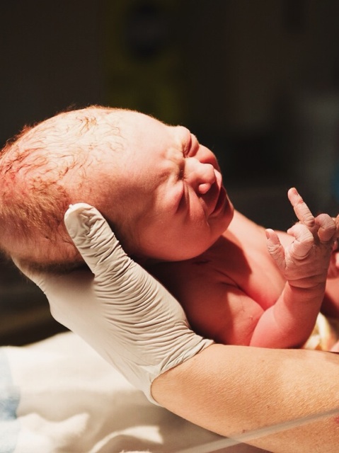 Newborn baby does not seem very happy with the outside world.