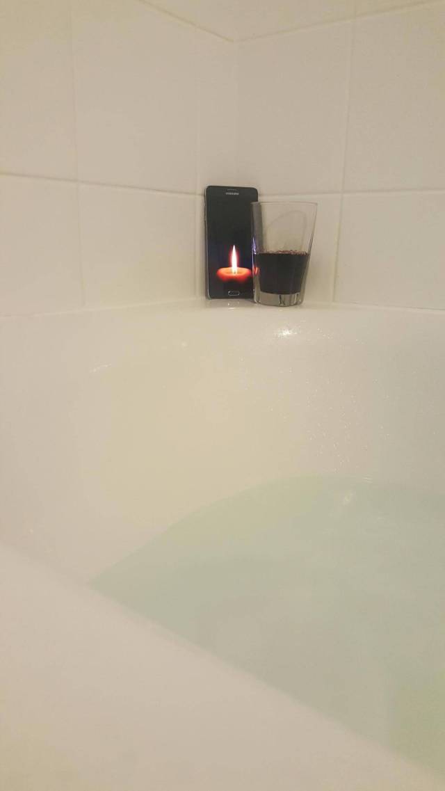 Relaxing bubble bath with a glass of wine and a candle.