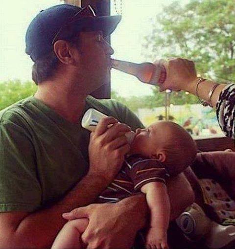 Dad feeds Baby some milk from a bottle while Mommy feeds Daddy some beer from a bottle. Such a beautiful sight.