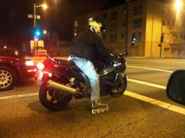 Motorcycle rider wearing rollerblades. It must be hard to shift but fun at stop lights.