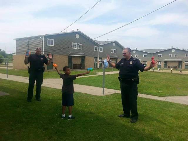 Two white police officers held at gunpoint by black kid.