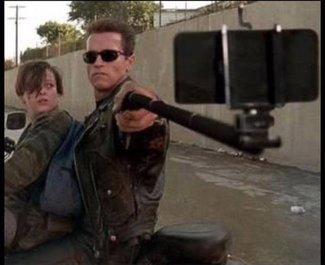 Vintage behind the scenes photo of Arnold Schwarzenegger taking a selfie in the movie Terminator 2: Judgement Day.