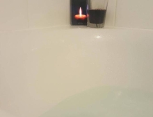Relaxing bubble bath with a glass of wine and a candle.