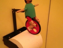 Toilet paper holder with guy riding a unicycle makes wiping your ass more fun.