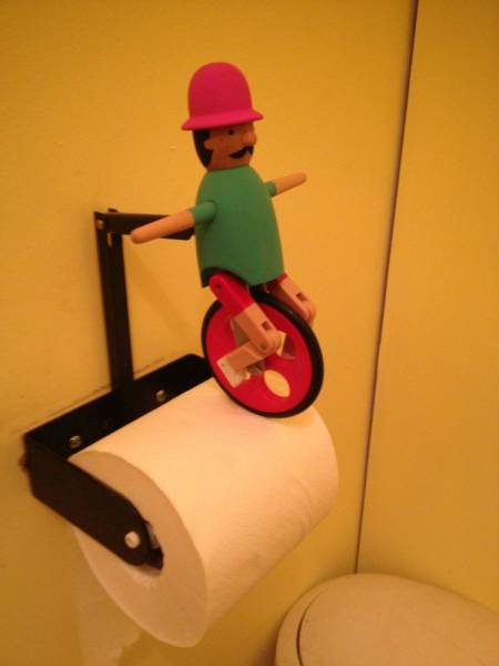 Toilet paper holder with guy riding a unicycle makes wiping your ass more fun.